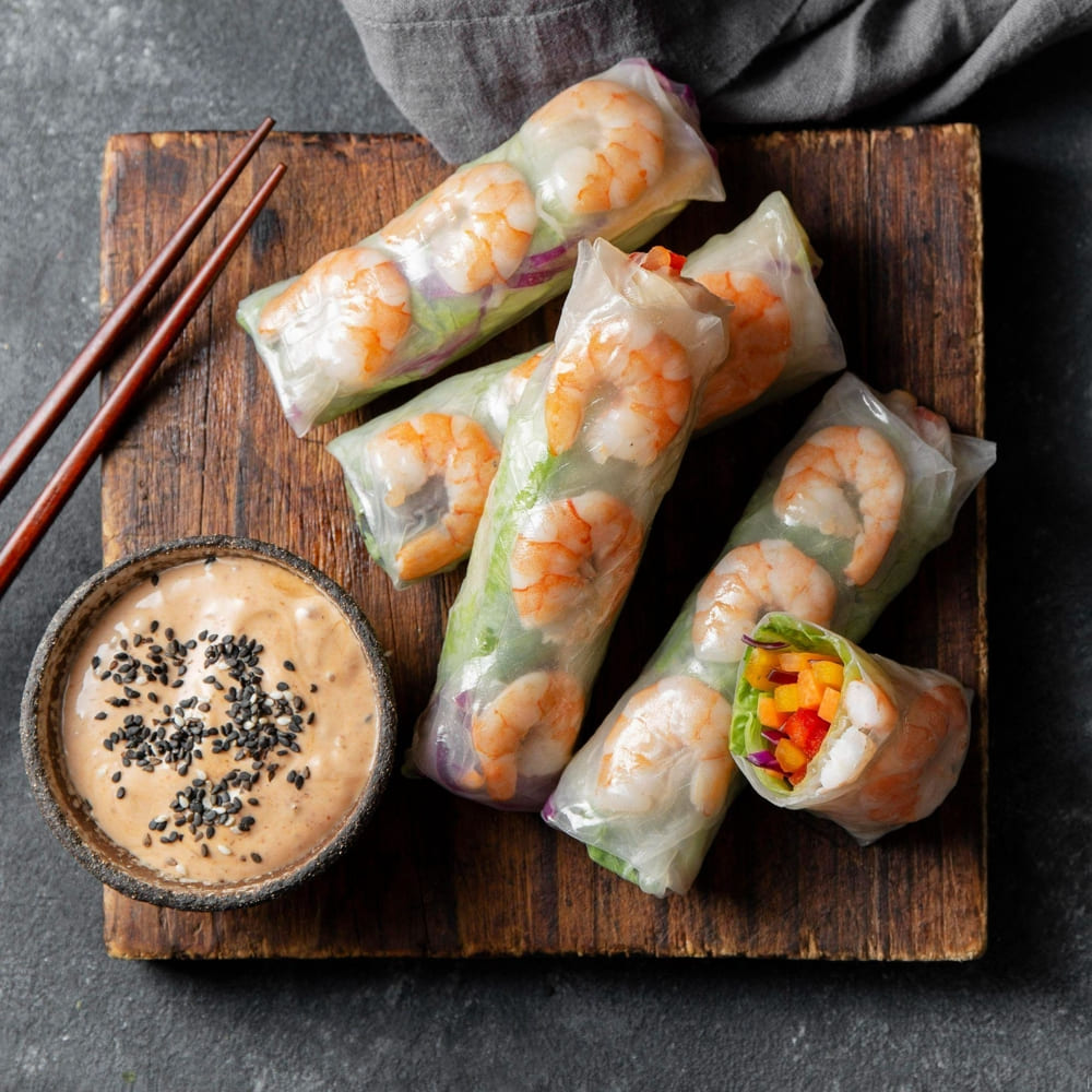 Goi Cuon, or fresh spring rolls, are translucent rice paper rolls filled with shrimp, pork, and herbs